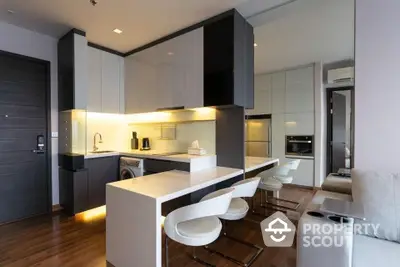 Sleek modern kitchen with integrated appliances, ample cabinetry, and a stylish breakfast bar opening to a cozy living area, perfect for entertaining.