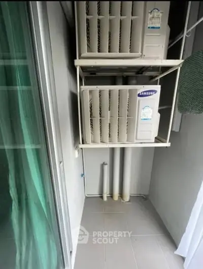 Compact balcony space with air conditioning units in modern apartment.