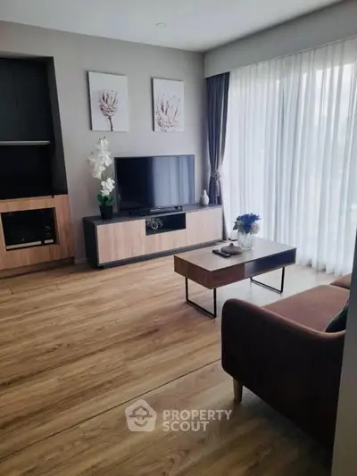 Modern living room with sleek furniture and large window, perfect for relaxation and entertainment.