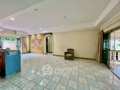 Spacious open-plan living room with tiled floors and large windows.