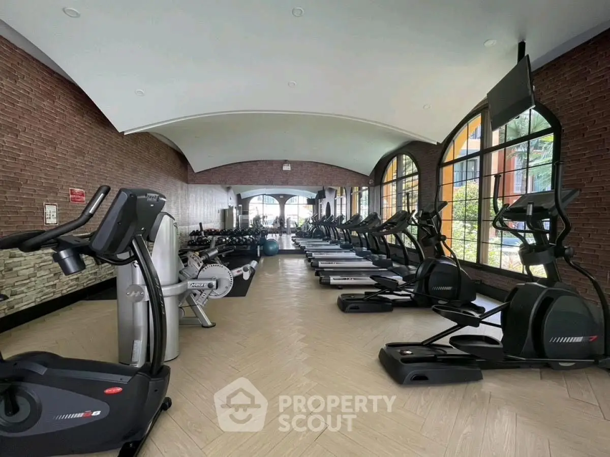 Spacious gym with modern equipment and large windows in luxury real estate property.