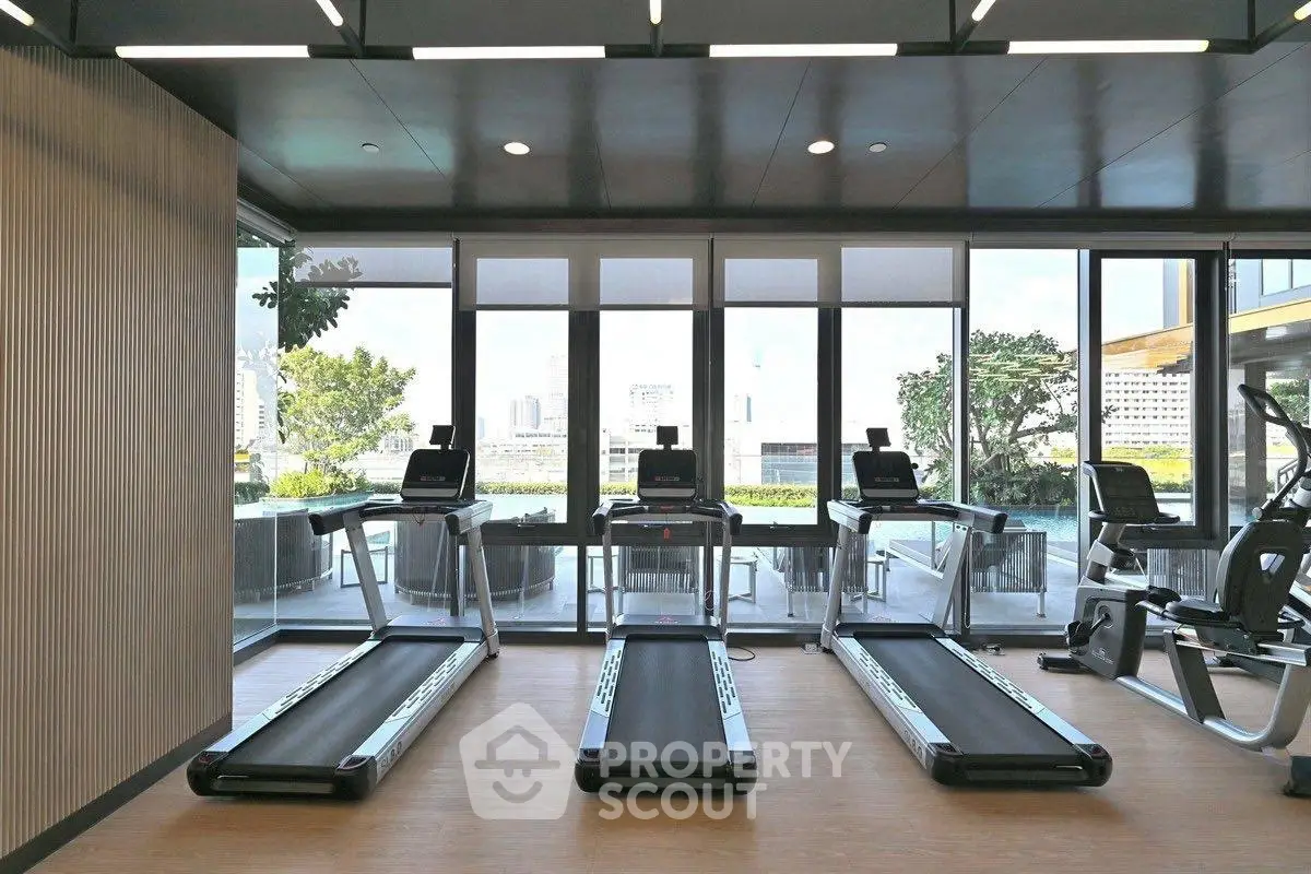 Modern gym with treadmills and city view in luxury apartment building.