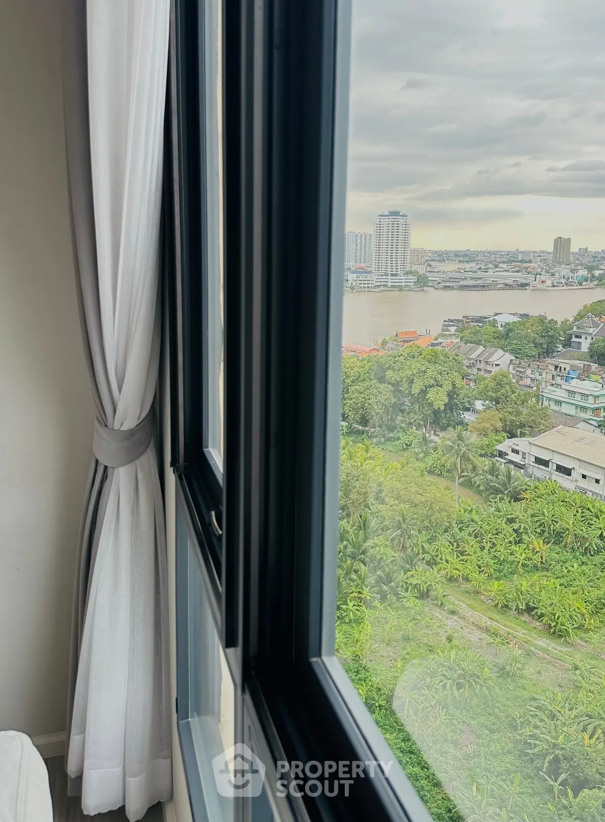 Stunning high-rise view of cityscape and river from a modern apartment window.