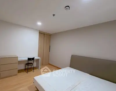 Spacious minimalist bedroom with modern furniture and ample natural light.