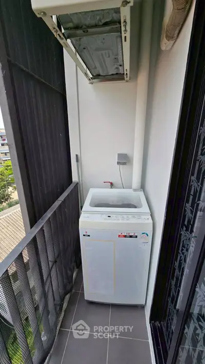Compact balcony with washing machine and air conditioning unit in modern apartment.