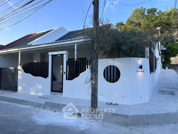 Modern white exterior house with unique circular window and sleek black gate