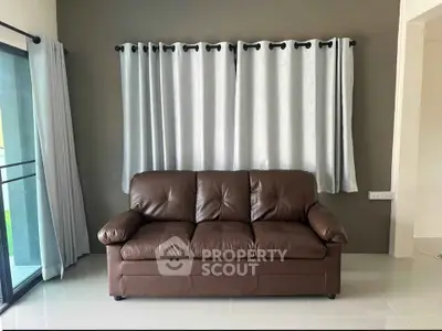 Modern living room with brown leather sofa and elegant curtains, perfect for cozy relaxation.