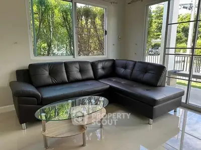 Modern living room with sleek black leather sectional and glass coffee table.