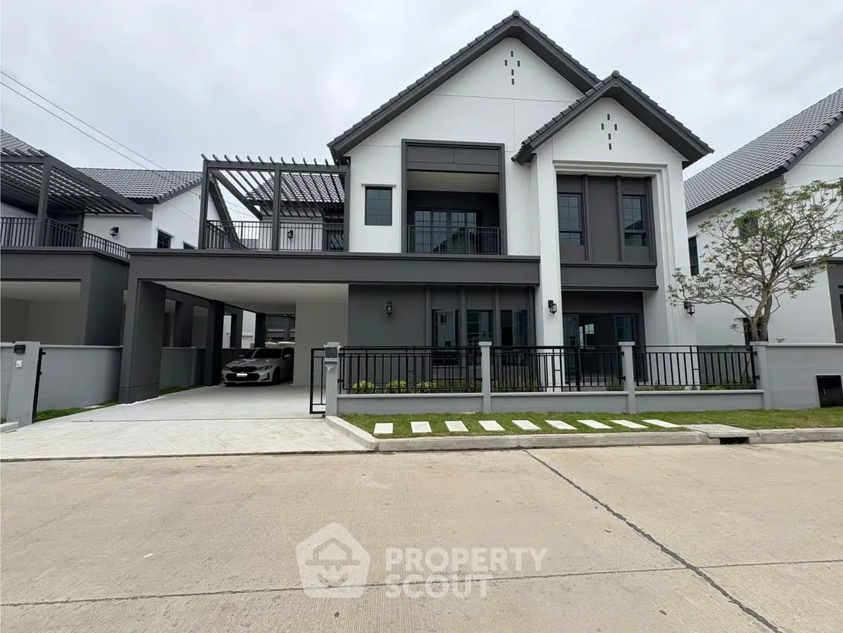 Modern two-story house with sleek design and spacious driveway in a suburban neighborhood.