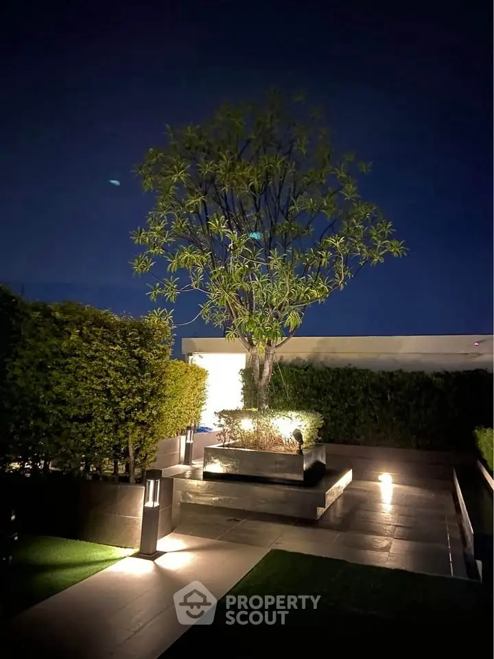 Luxurious rooftop garden with ambient lighting and lush greenery at night.