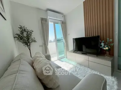 Modern living room with cozy sofa, TV, and balcony access, featuring stylish decor and natural light.