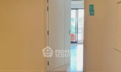 Inviting entrance to a modern apartment with a glimpse of a bright living area and balcony.