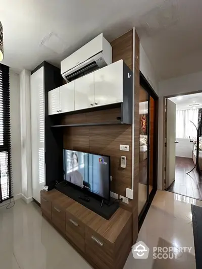 Modern living room with sleek TV setup and air conditioning in stylish apartment.