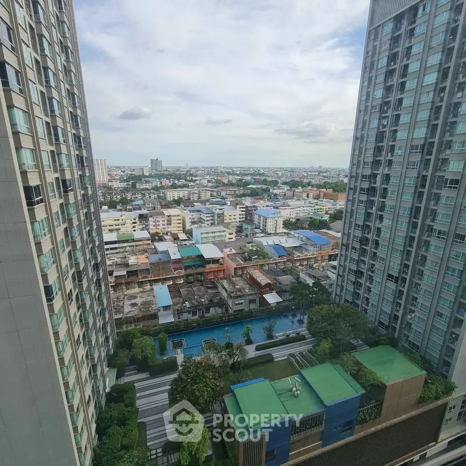 Stunning cityscape view from high-rise apartment with pool and lush greenery below.
