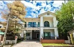 Charming two-story house with lush greenery and spacious driveway
