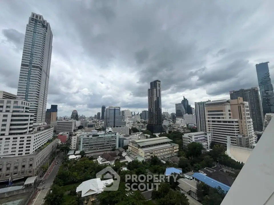 Stunning cityscape view showcasing modern skyscrapers and lush greenery under a dramatic cloudy sky.