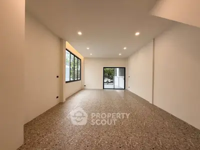 Spacious modern living room with large windows and terrazzo flooring, offering a bright and airy ambiance.