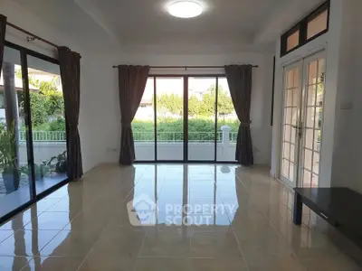 Spacious living room with large windows and garden view, perfect for natural light lovers.