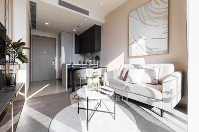 Modern living room with elegant decor and open kitchen layout, featuring a cozy sofa and stylish artwork.