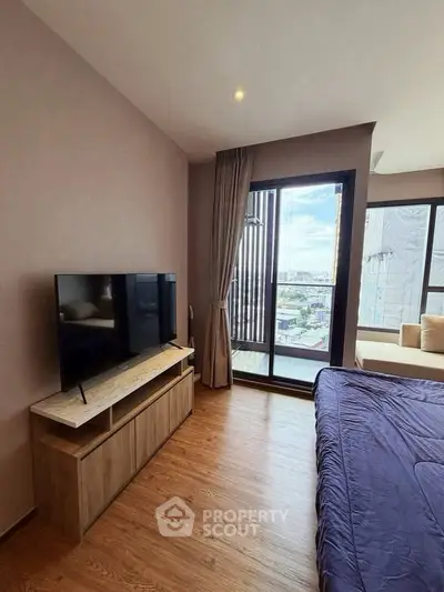 Modern bedroom with large window and city view, featuring a sleek TV stand and cozy bed.