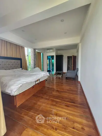 Spacious bedroom with wooden flooring and modern furnishings in a luxury apartment.