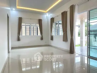 Spacious modern living room with large windows and pool view, featuring elegant curtains and glossy tile flooring.