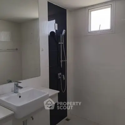 Modern bathroom with sleek fixtures and natural light from a small window.
