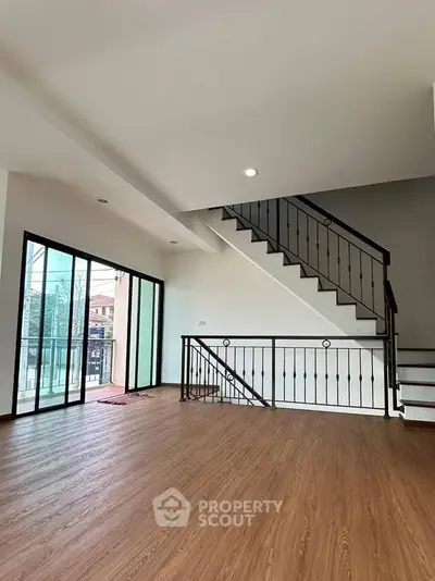 Spacious modern living room with wooden flooring and stylish staircase