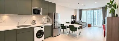 Modern open-plan kitchen and living area with sleek appliances and stylish decor in a high-rise apartment.