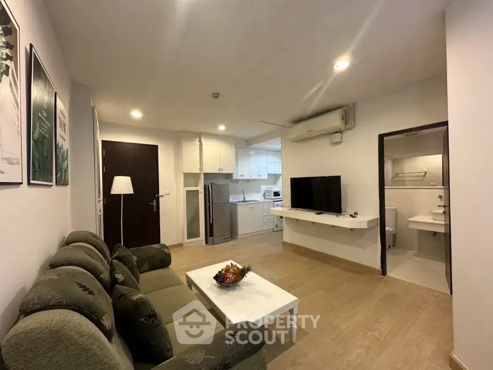 Modern living room with open kitchen and cozy seating area in a stylish apartment.