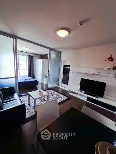 Modern open-plan living room with sleek furniture and stylish decor, featuring a cozy bedroom area.