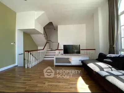 Spacious living room with modern staircase and cozy seating area, perfect for relaxation and entertainment.