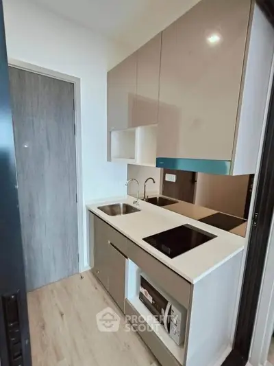 Modern compact kitchen with sleek cabinetry and built-in appliances in a stylish apartment.