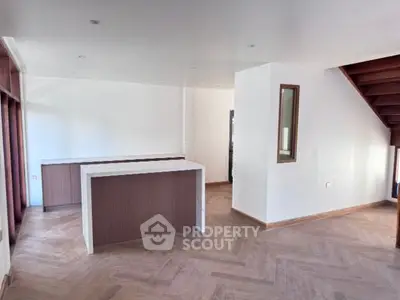 Spacious open-plan living area with modern wooden flooring and staircase