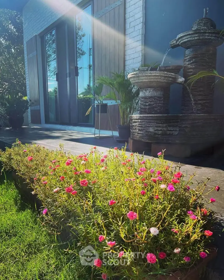 Charming garden with blooming flowers and elegant water fountain at modern home entrance