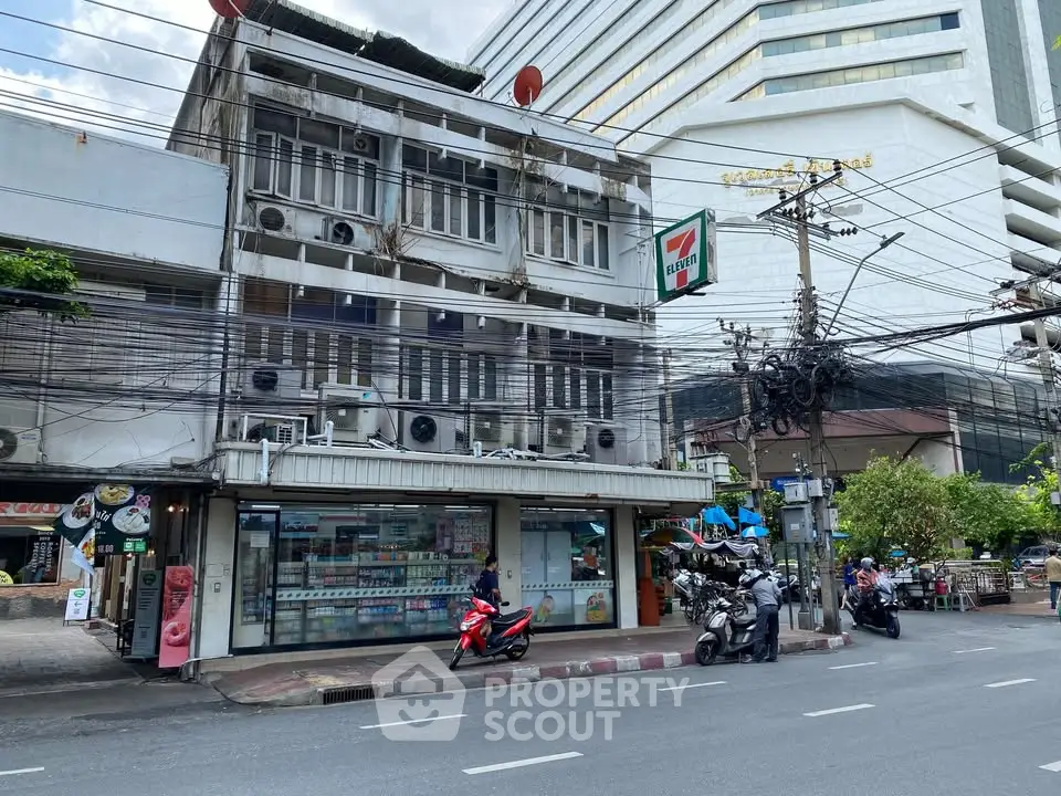 Street view of commercial building with convenience store and motorbikes parked outside.