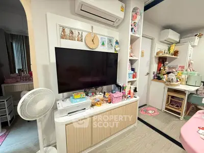 Charming living room with modern decor, featuring a wall-mounted TV, air conditioning, and stylish storage solutions.