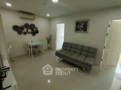 Modern living room with sleek sofa and dining area, featuring elegant wall decor and bright lighting.