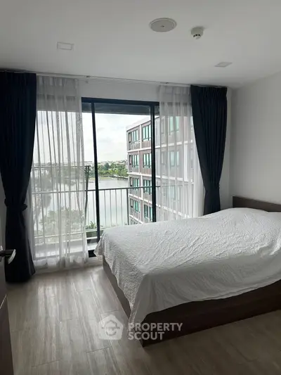 Modern bedroom with large window and stunning view of cityscape and water.