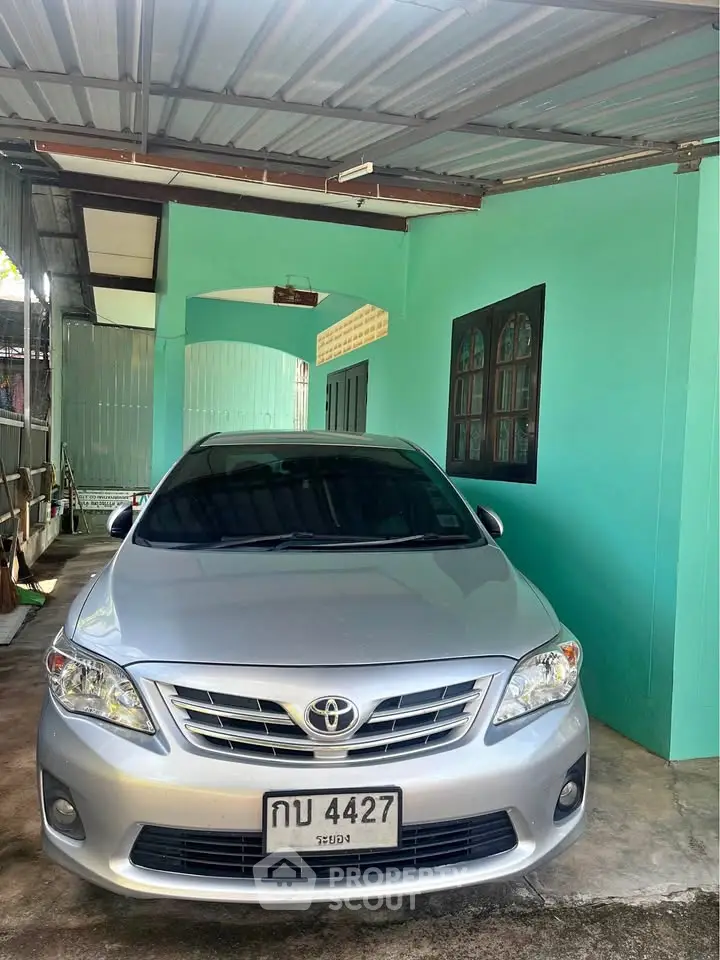Covered parking space with a silver car in a vibrant turquoise-painted area, showcasing practical home parking.
