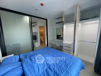 Modern bedroom with blue bedding, sliding closet doors, and a small workspace.
