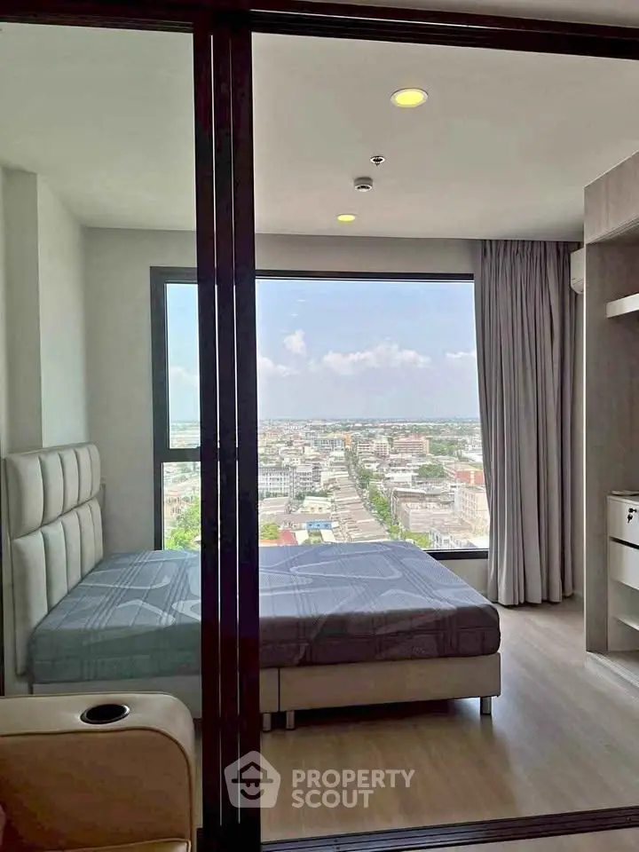 Modern bedroom with large window offering stunning city view in high-rise apartment.