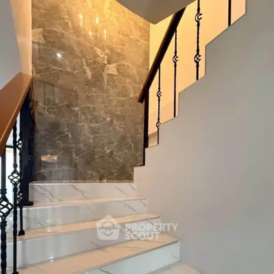 Elegant staircase with marble steps and decorative railing in modern home