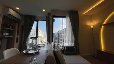 Modern living room with large windows and city view, featuring elegant dining setup and ambient lighting.