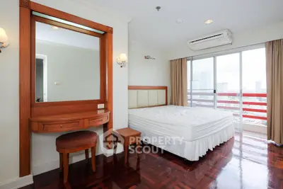 Spacious bedroom with elegant wooden furniture and city view balcony.