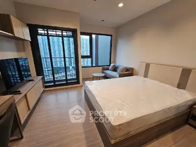 Modern bedroom with city view, featuring a cozy bed and stylish decor in a high-rise apartment.