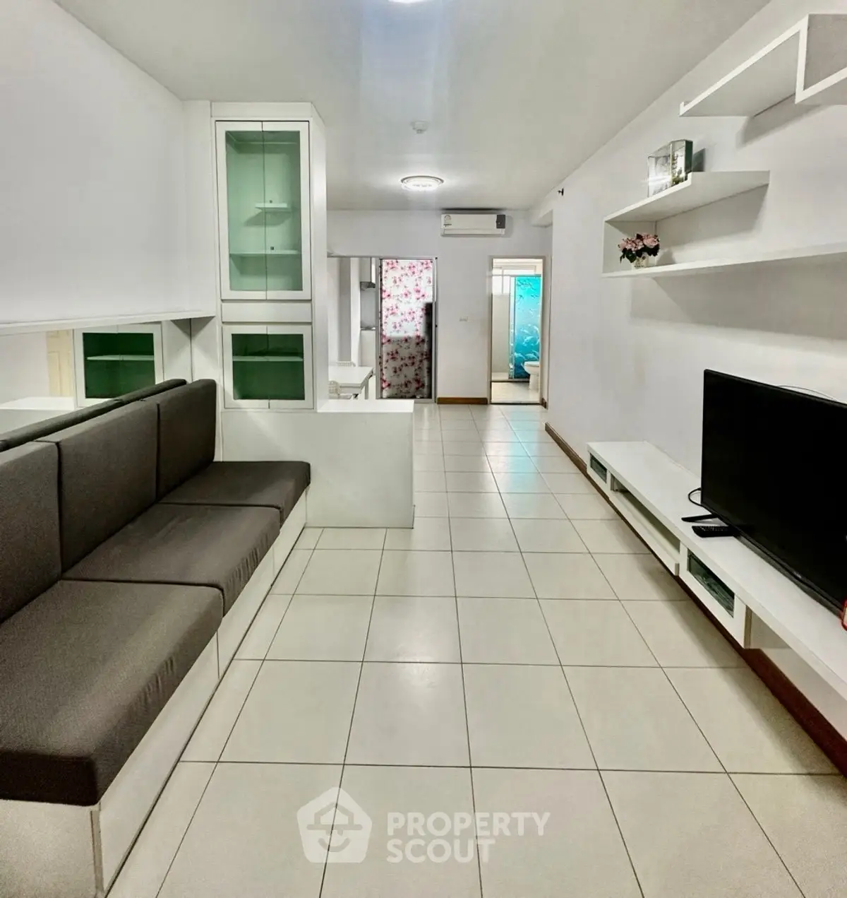 Spacious modern living room with sleek furniture and tiled flooring, perfect for comfortable living.