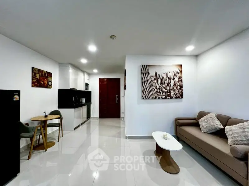 Modern living room with sleek kitchen and stylish decor in open layout apartment.