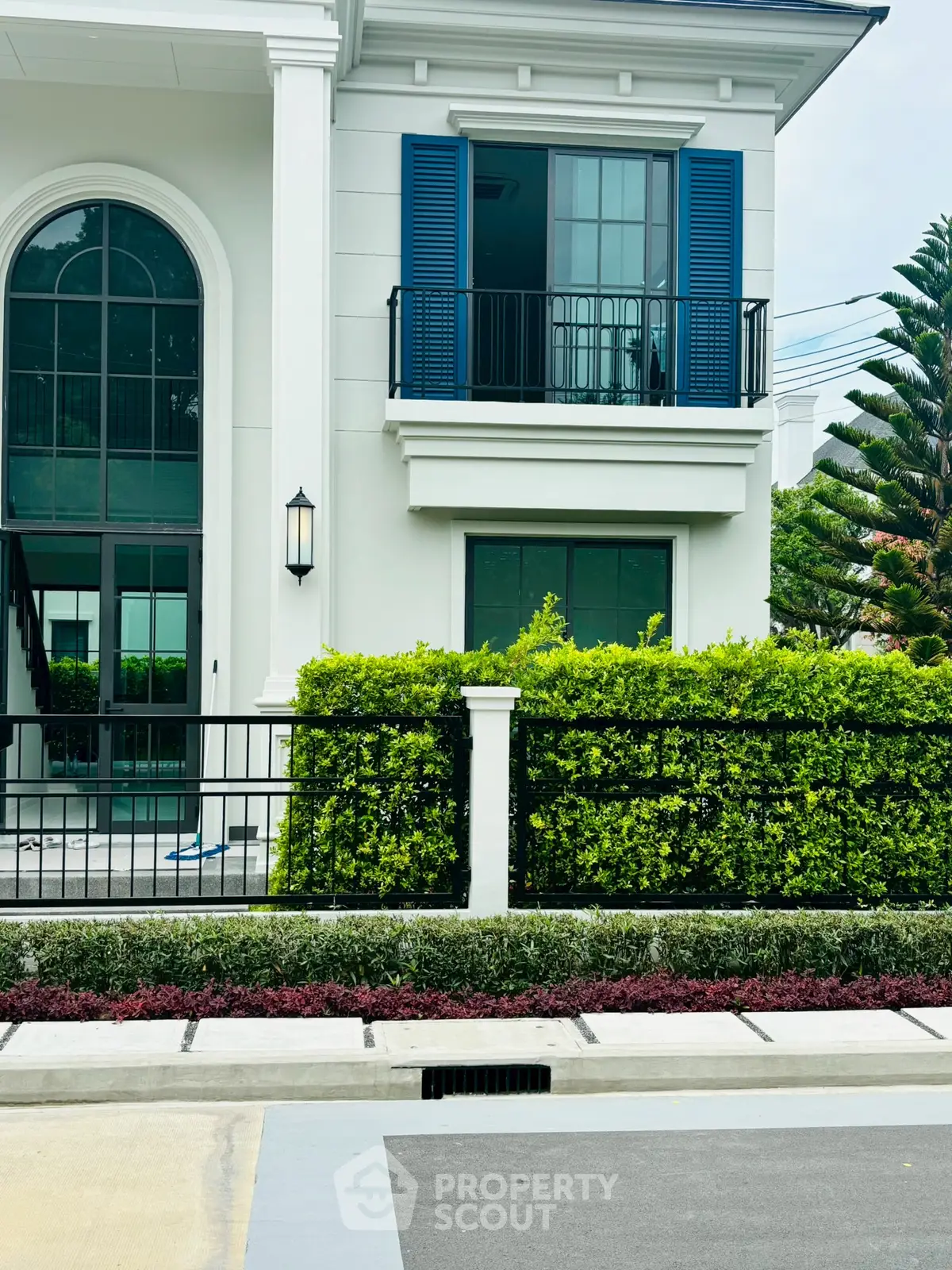 Elegant modern house exterior with lush greenery and stylish blue shutters.
