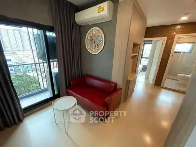 Modern apartment interior with red sofa, wall clock, and balcony view.